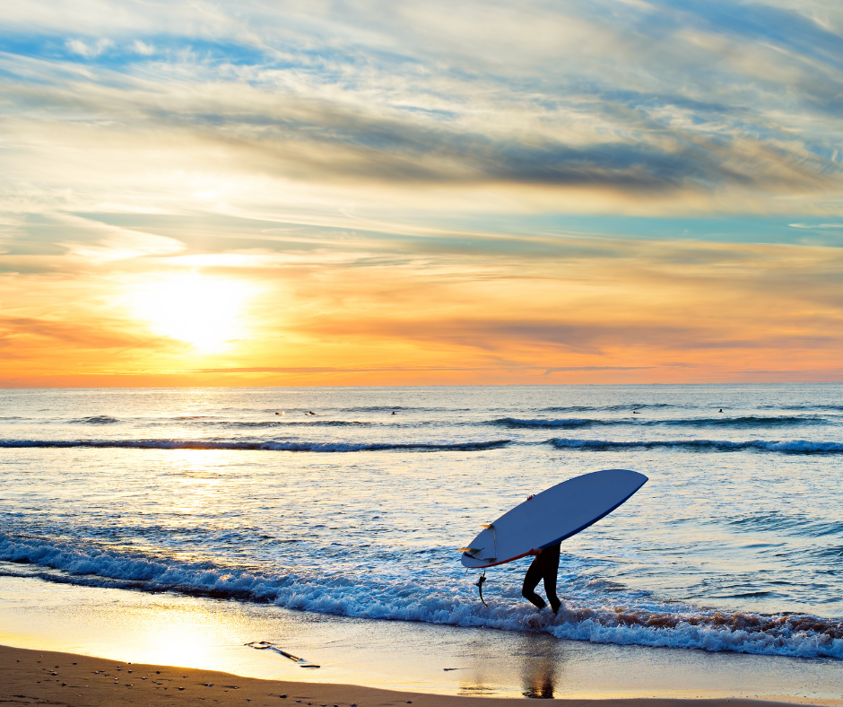 ocean, beach and a surfer walking